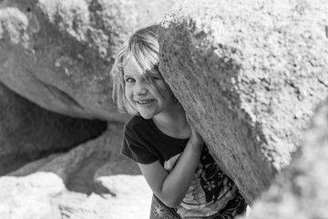 Little girl peeking out from rock