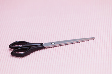 Detailed closeup of hairdressing scissors on pink background