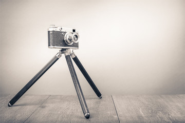 Retro old outdated manual film camera circa 1950s on wooden table. Vintage style sepia photo