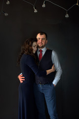 A beautiful loving couple in a living room at home on black background. A youth couple in love