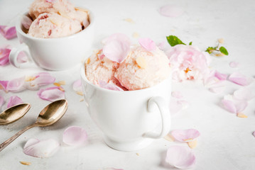 Summer refreshing desserts. Vegan diet food. Ice cream with rose petals and slices of almond, in white serving bowls, on a white concrete table. Copy space
