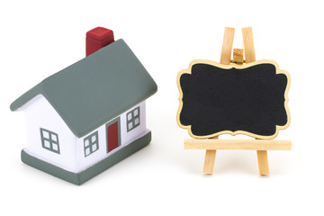 Blackboard label and miniature model of house isolated on white background, copy space