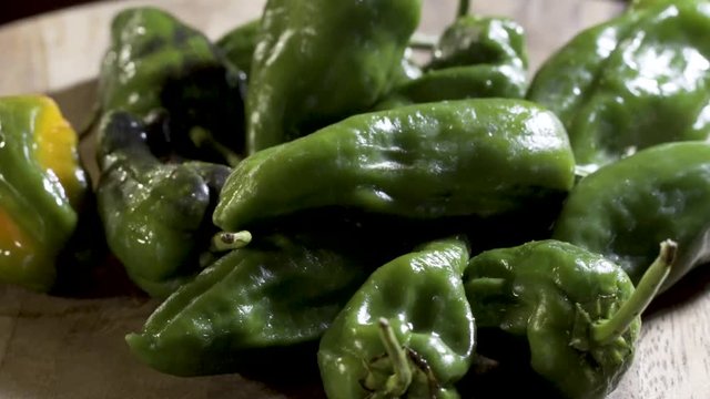 Extreme closeup of sweating padron peppers slowly turning for the camera.