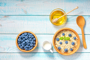 Healthy breakfast with oat flakes, natural milk, fresh blueberries. Top view.