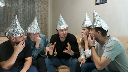 Group of people with foil on their heads discussing conspiracy theories. Friends with foil on their...
