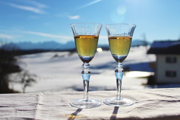 Close up: Brandy in Vintage-Gläsern auf dem Balkon, traumhafte Winterlandschaft im Hintergrund