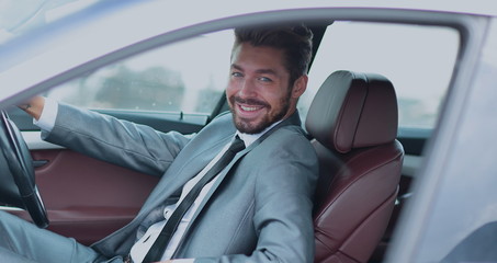 Portrait of an handsome smiling business man driving his car