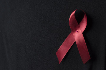red ribbon (aids ribbon) on black cloth background.Aids / HIV Concept. healthcare and medical concept