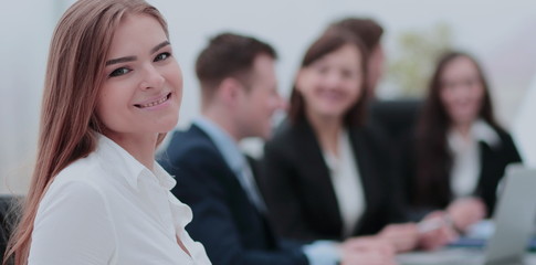 Portrait of a smiling businesswoman sitting at a table with coll