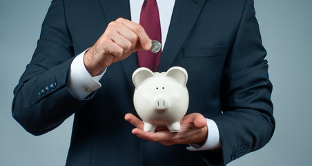 Finance Savings concept. Businessman in suit is holding piggy bank.