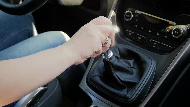 Slow motion closeup video of young woman shifting car manual gearbox