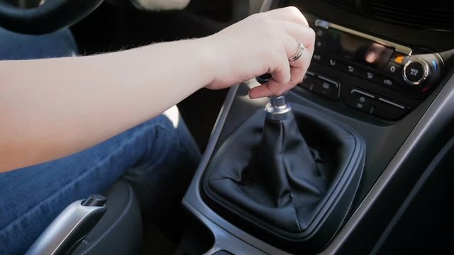 Closeup slow motion footage of young woman driving car with manual gearbox