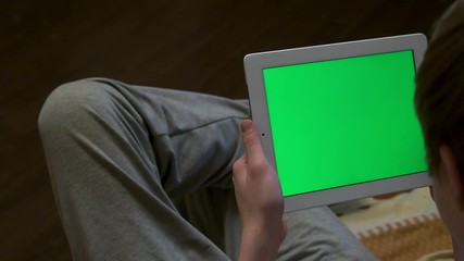 Rear view of blurred man holding a tablet with a blank editable green screen. Man holding tablet with green screen - back view