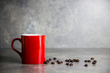 red cup of coffee and coffee bean with concrete background
