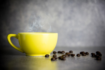 yellow cup of coffee and coffee bean with concrete background