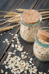 Dry rolled oats or oat flakes in craft glass jars with oat spikes or spikelets