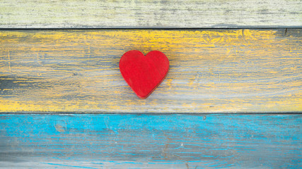 A simple red heart on a colorful wood plank background.