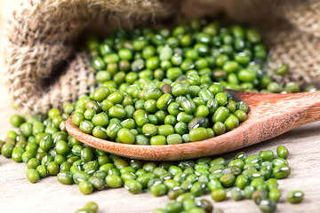 close up green mung beans in wooden spoon on wood plate