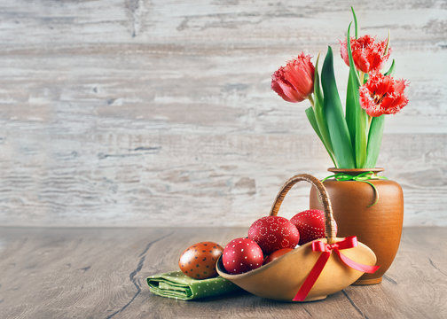 Red tulips and painted Easter eggs on wood, text space