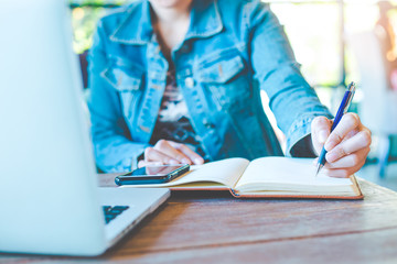 Woman hand writing on notepad with a pen in the office.