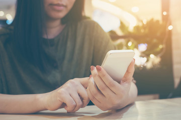 Asian women using smartphone in restaurant, She is typing messages with her friends through the chat application on mobile phone