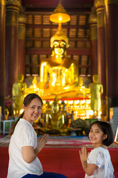 Asian daughter and mother making worship to the Buddha statue in temple
