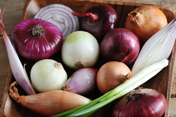 different onion varieties in a wooden plate - a selection of onion