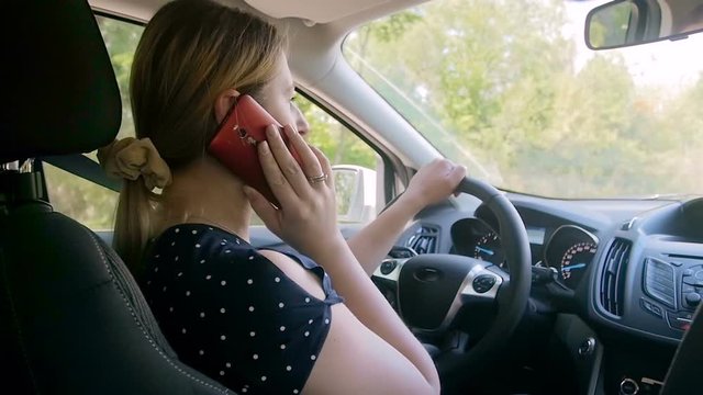 Slow motion video of young owman talking by phone while driving car