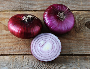 whole and half onions in red on rough wooden background
