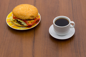 Delicious hamburger and cup of coffee on wooden table