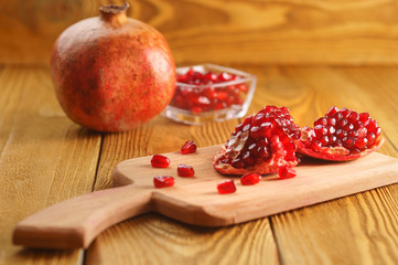 Pomegranate seeds on a wooden board, glass cup