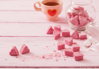 Granulated pink sugar  in the shape of heart and cup of tea  on a wooden background