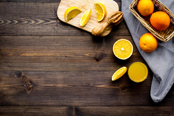 Squeeze juice from oranges. Juicer and slices of oranges on dark wooden background top view copyspace