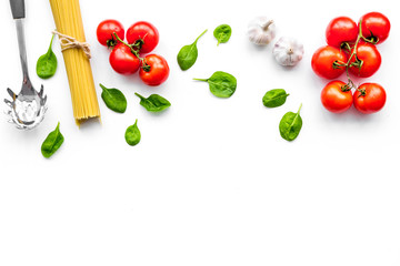 Naklejka na ściany i meble Cooking italian pasta. Spaghetti, tomatoes, garlic, basil and cookware on white background top view copyspace