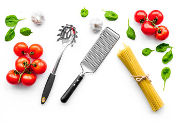 Cooking italian pasta. Spaghetti, tomatoes, garlic, basil and cookware on white background top view