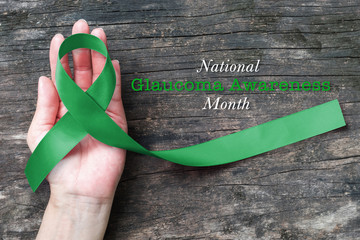 National Glaucoma Awareness Month in January with Green ribbon on helping hand (bow isolated with...