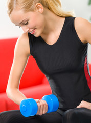Young happy smiling woman with dumbbells, indoors