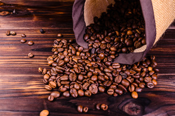 Roasted coffee beans in sack on wooden table