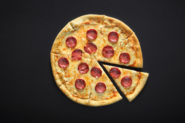 pizza peperoni on black stone background