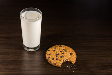 Chocolate chip cookies and glass of milk on wooden table