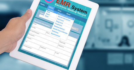 Hand holding tablet computer show medical record system.