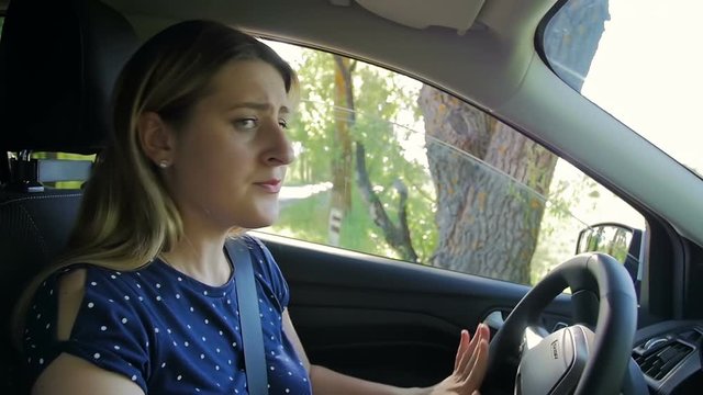 Slow motion footage of young woman reversing and turning on road. Driver looking at side view mirrors