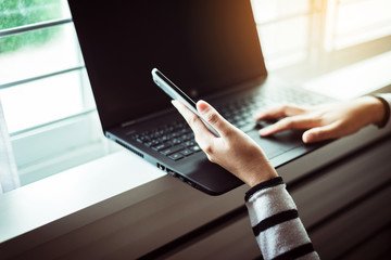 Fototapeta premium Woman holding mobile phone and using laptop computer with shopping onling,Selective focus