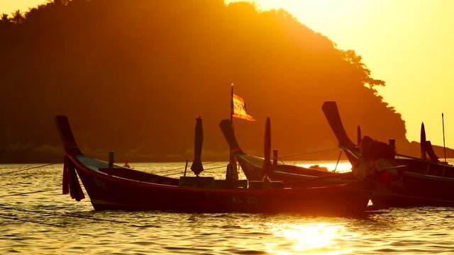 Group of long tail boat or boat excursions floating in the andaman sea with golden light of sunset and  boat background in travel or transportation concept.