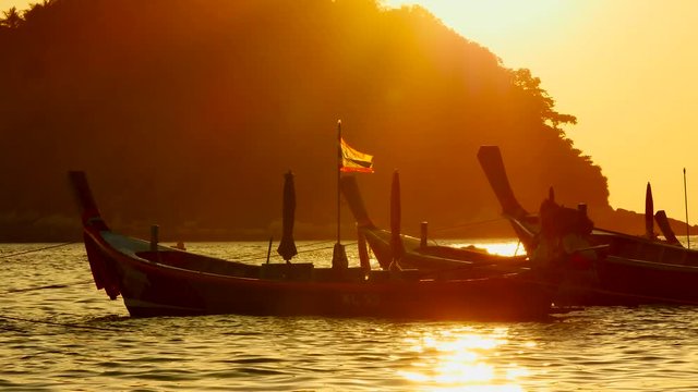 Group of long tail boat or boat excursions floating in the andaman sea with golden light of sunset and  boat background in travel or transportation concept.