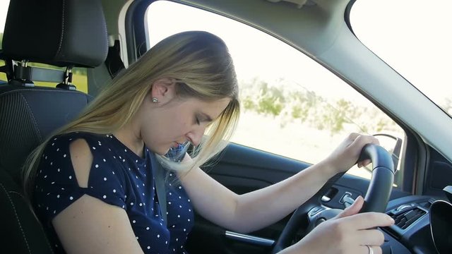 Slow motion footage of young owman falling asleep while driving car at countryside road