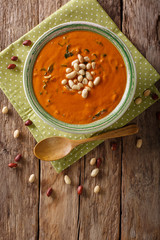 Peanut puree soup with greens close-up on a table. Vertical top view