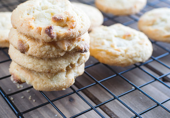 Stack of fresh white chocolate macadamia nut cookies cooling on wire grid.