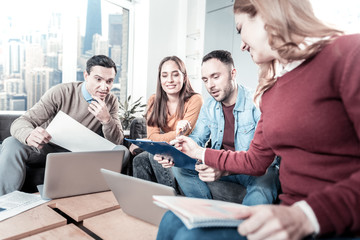 Pay attention. Reliable calm confident employees sitting together in the office working with the document and focusing on it.