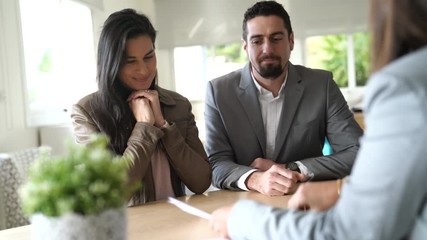 Couple in bank office signing loan agreement